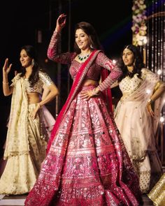 a woman in a red and gold lehenga with other women standing around her