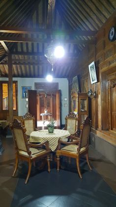 a dining table and chairs in a room with wood paneled walls, ceiling fan and wooden framed windows