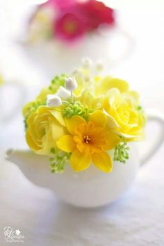 yellow and white flowers in a tea pot