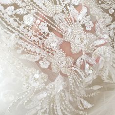 a close up view of the back of a wedding dress with white flowers on it