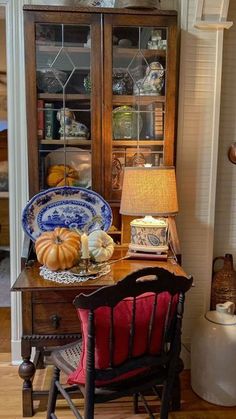 an old china cabinet with plates and pumpkins on it