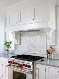 a stove top oven sitting inside of a kitchen next to white cabinets and counter tops