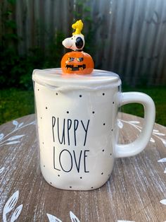 a white coffee mug with a dog figurine on top that says puppy love