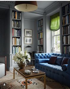 a living room with blue couches and bookshelves full of books on the shelves