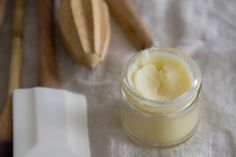 an open jar of cream next to wooden spoons