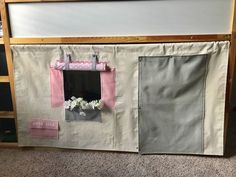 a white and pink play house with flowers in the window