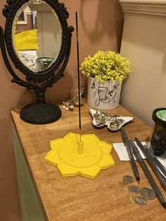 a mirror and some scissors on a wooden table next to a vase with flowers in it