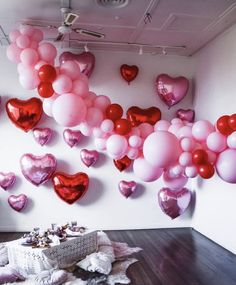 a room filled with lots of pink and red heart shaped balloons hanging from the ceiling