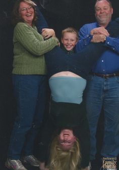 a group of people standing next to each other in front of a man upside down