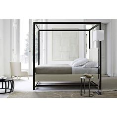 a bedroom with white walls and flooring, an iron bed frame is in the center of the room