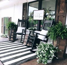 black and white striped rug on porch with rocking chairs, potted plants and welcome sign