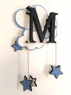 the letter m is made up of wooden stars and hangs on a rope with twine