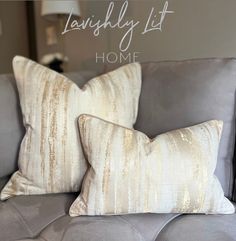 two pillows sitting on top of a gray couch in front of a wall with the words, lavishly lit home