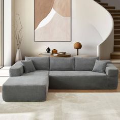 a living room with a sectional couch and coffee table in front of a spiral staircase