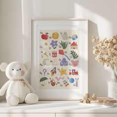 a white teddy bear sitting next to a framed art print