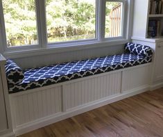 a window seat in the corner of a room with a book shelf and bookshelf