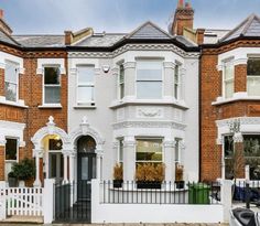 a row of houses with white picket fence and black gate in front of the house