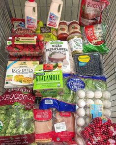 a shopping cart filled with lots of food and condiments on top of it