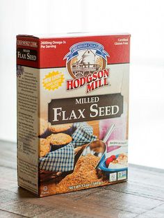 a box of flax seed sitting on top of a wooden table next to a spoon