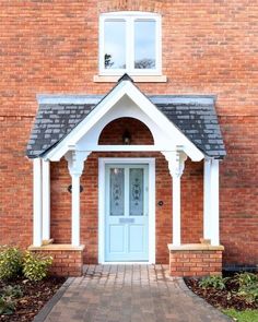 a brick house with a blue front door and white trim on the side walk leading up to it