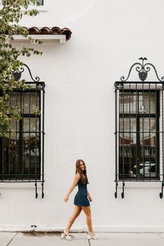 a woman walking down the street in front of a white building