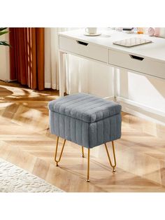 a blue foot stool sitting on top of a wooden floor next to a white desk