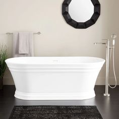 a white bath tub sitting on top of a bathroom floor next to a mirror and shower head