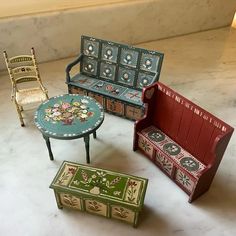 four miniature furniture sitting on top of a white floor next to a table and chair