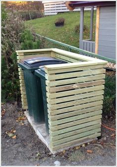 two trash cans sitting next to each other in front of a fenced off yard