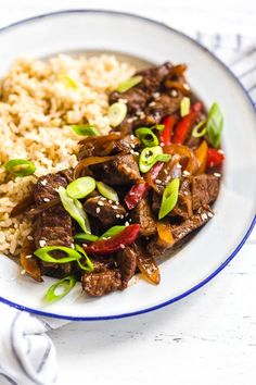 a white plate topped with rice and beef next to broccoli covered in sauce