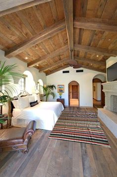 a bedroom with wood floors and white bedding in the center, along with an area rug on the floor