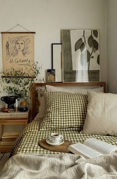 a bed with pillows and blankets on top of it next to a wooden table filled with books