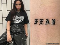 a woman sitting next to a wall with the word fear tattooed on her arm and leg