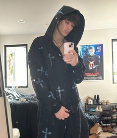 a young man in a black hoodie taking a selfie with his cell phone