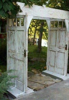 two white doors are open in a garden