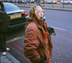 a woman walking down the street while talking on her cell phone and holding a dog