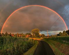 two rainbows in the sky over a rural road