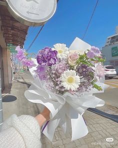 a woman holding a bouquet of flowers on the street