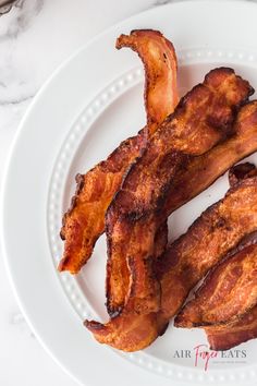 bacon strips on a white plate sitting on a marble table