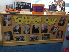 a wooden table with pictures on it and toys hanging from the wall in front of it