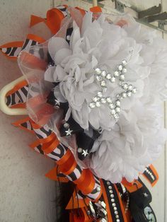 an umbrella decorated with white flowers and orange ribbons is hanging on the front door for halloween