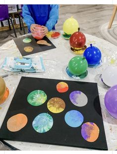 a table with balloons and other items on it, including paper plates that look like planets