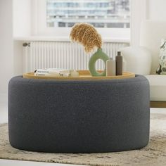 a round ottoman with a hair dryer and other items on it in front of a window