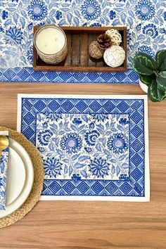 blue and white placemats with pine cones on them next to a candle holder