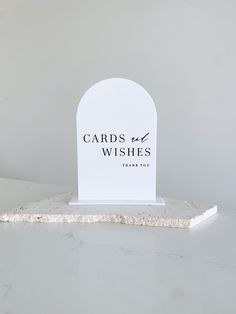 a white card holder sitting on top of a marble slab with the words cards and wishes printed on it