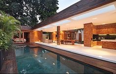 an outdoor swimming pool surrounded by greenery and wooden beams with lights on the ceiling