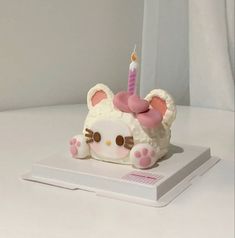 a hello kitty cake with a lit candle on it's top, sitting on a white surface