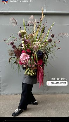 a woman walking down the street carrying a large bouquet