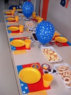 a table set up for a birthday party with balloons, plates and cups on it