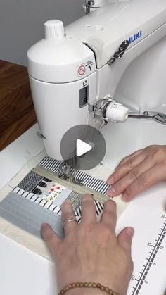 a woman is using a sewing machine to sew fabric on the table top with her hands